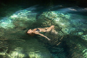 Woman floating in water in a relaxed pose in a pool situated in a cenote.Getty Images #150086968