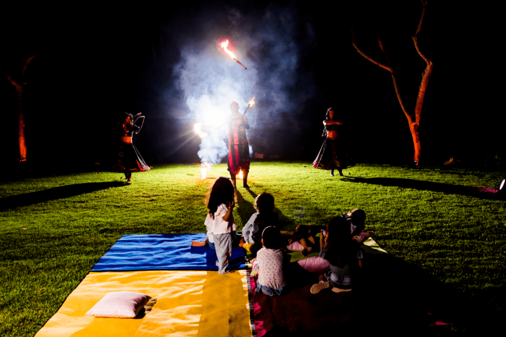 children watching a fire show lying in the garden of Grand Velas Riviera Maya